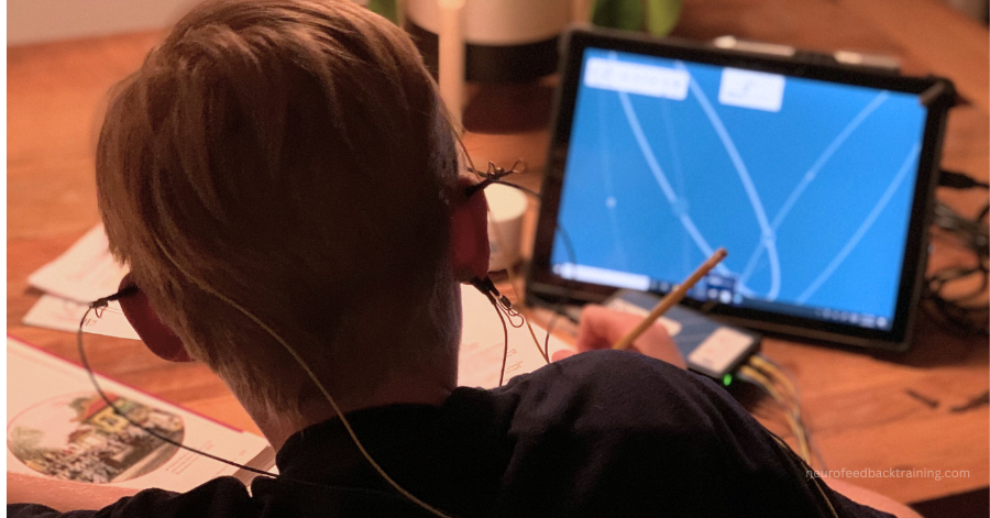 child focusing on homework while doing a neurofeedback session